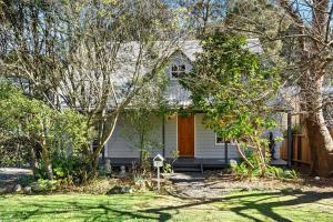 ein weißes Haus mit einem Garten mit Bäumen in der Unterkunft Bunyip Cottage in Katoomba