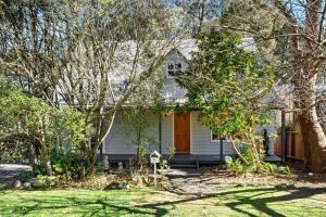 a white house with a yard with trees at Bunyip Cottage in Katoomba