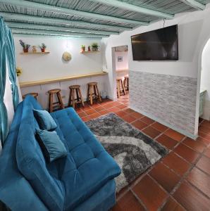 ein Wohnzimmer mit einem blauen Sofa und einer Bar in der Unterkunft PUEBLITO BOYACENSE - Hospedaje El Cocuy in Duitama
