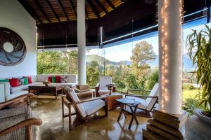 a living room with a large window and furniture at Madulkelle Tea and Eco Lodge in Kandy