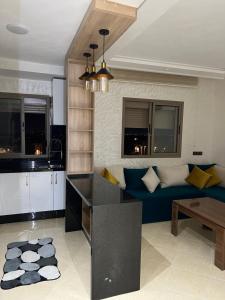 a kitchen and a living room with a blue couch at L'horizon Aéroport Appartement in Marrakech
