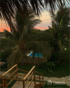 a wooden chair sitting under a palm tree next to a pool at Panorama garden inn in Máncora