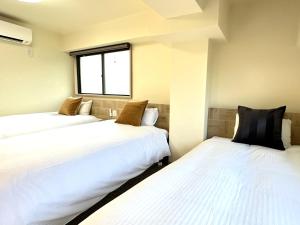 伊東市にあるガーランドコート宇佐美 GarlandCourt Usamiの白いシーツが備わるベッド3台、窓が付いた客室です。
