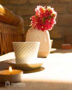 Panorama garden inn في مانكورا: مزهرية مع الزهور تجلس على طاولة مع شمعة