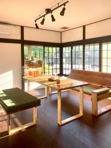 Habitación grande con mesa de madera y bancos. en 一棟貸宿　奥入瀬屋 en Yakeyama