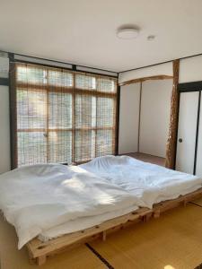 a large bed in a room with windows at 一棟貸宿　奥入瀬屋 in Yakeyama