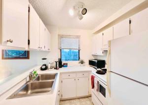 ホノルルにある28th Floor Breathtaking Ocean View with a Kitchen-Free Parking-Corner Unit-King Bedのシンクと冷蔵庫を備えた白いキッチン