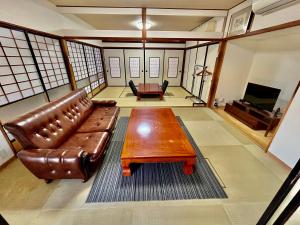 a living room with a leather couch and a coffee table at オオヤシロSTAY旅音 in Izumo