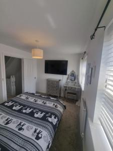 a bedroom with a bed and a flat screen tv at Cosy townhouse near Kidwelly in Kidwelly