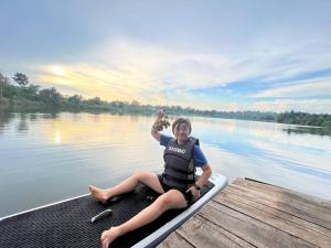 Una donna seduta su una barca su un molo di Tam An Lakeview House a Buôn Ma Thuột