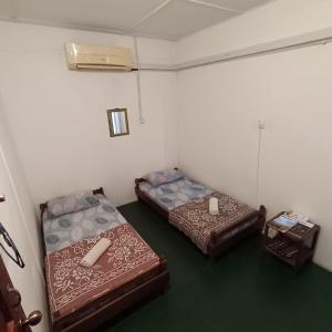 two beds sitting in a room with a green floor at Tabun Homestay in Miri