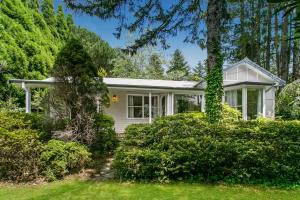 Garden Cottage في ليورا: بيت ابيض فيه اشجار وشجيرات