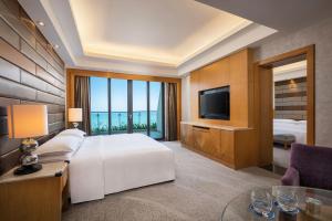 a hotel room with a bed and a television at Four Points by Sheraton Hainan, Sanya in Sanya