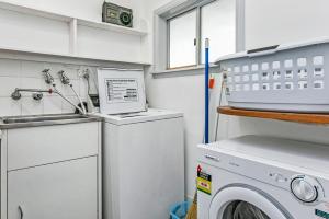 uma cozinha com uma máquina de lavar roupa e um lavatório em Garden Cottage em Leura