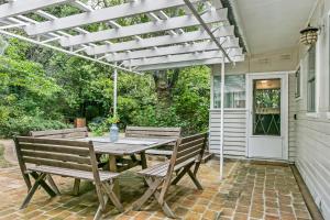 eine Terrasse mit einem Holztisch und Bänken in der Unterkunft Garden Cottage in Leura + 10 Fotos