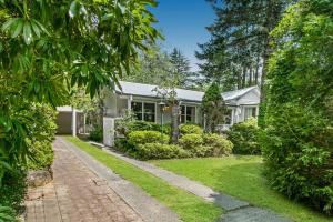 ein weißes Haus mit Ziegelsteinfahrt und Bäumen in der Unterkunft Garden Cottage in Leura