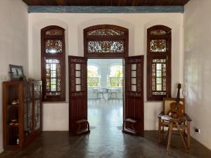 a room with wooden doors and a table and a guitar at Foozoo Mantra Weligama in Weligama