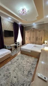 a bedroom with two beds and a tv and a table at OLD STREET Guest House in Samarkand