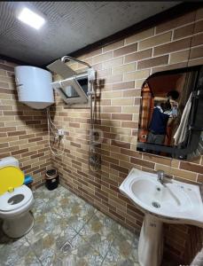 La salle de bains est pourvue de toilettes, d'un lavabo et d'un miroir. dans l'établissement A frame for families, à Quba