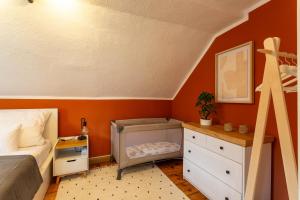 1 dormitorio con paredes de color naranja, 1 cama y vestidor en Moderne Ferienwohnung mit Festungsblick im Zentrum, en Königstein