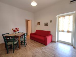 un soggiorno con divano rosso e tavolo di Masseria Don Egidio a Melendugno