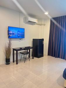 Habitación con mesa y TV en la pared. en AB House, en Ban Thung Thong