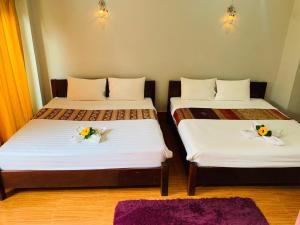 Dos camas en una habitación con flores. en Inthila Garden Guest House en Vang Vieng