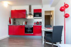 a kitchen with red cabinets and a table with a chair at SWEETHOME DIJON - ALBERT 1er in Dijon