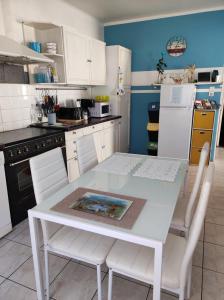 een keuken met een witte tafel en witte stoelen bij Chambre chez l'habitante "Bambou" in Derval