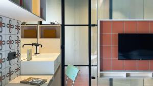 a bathroom with a sink and a tv on a wall at Le stanze di Caterina in Cesenatico