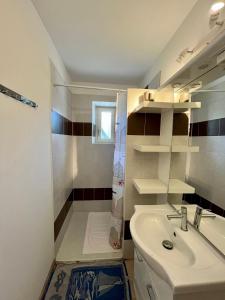 y baño blanco con lavabo y ducha. en Gîte le Tour 45 m2 Cévennes Lozère, en Le Collet-de-Dèze