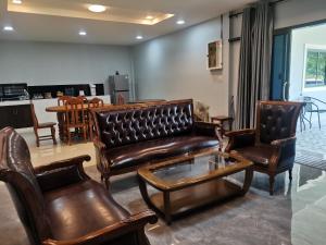 a living room with leather furniture and a table at Numhom Resort in Ban Nong Chum Saeng