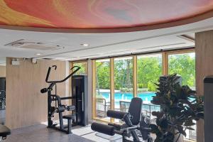een kamer met een fitnessruimte met fitnessapparatuur en een zwembad bij OLIVE SKY @ ATMOZ BANGNA (SI IAM MRT.) in Ban Khlong Samrong