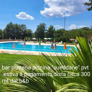 una piscina con sombrillas y un cartel para un complejo en B&B Kikina, en Austis