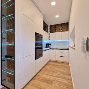 a kitchen with white cabinets and wood floors at APARTMAN LORINČIK KOSICE in Košice
