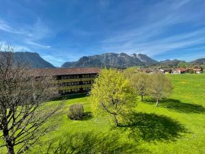 a building in a field with mountains in the background at Lindenhof Inzell - FeWo mit Chiemgaukarte in Inzell