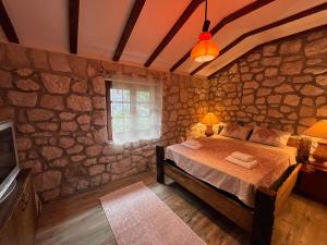 een slaapkamer met een bed en een stenen muur bij Bed & Wine Djonovic in Virpazar