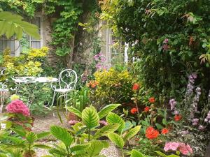 a garden with a table and chairs and flowers at la glycine in Asnelles