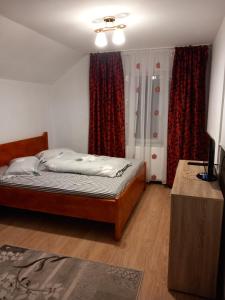 a bedroom with a bed and a window with curtains at CASA LAVINIA CRASNA GORJ in Crasna