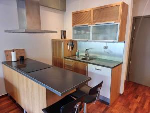 uma cozinha com um lavatório e um balcão com cadeiras em Kjekk urban leilighet em Stavanger
