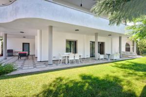 Un patio al aire libre con muebles blancos y césped. en Villa Estia - nel cuore della Valle D'Itria, en Cisternino