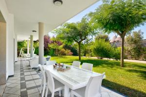 una mesa blanca y sillas blancas en el patio en Villa Estia - nel cuore della Valle D'Itria, en Cisternino