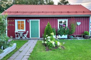 een rood huis met een groene deur in een tuin bij Cabin located in a traditionally Swedish setting! in Umeå