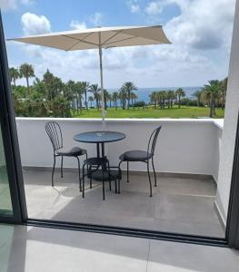 eine Terrasse mit einem Tisch, Stühlen und einem Sonnenschirm in der Unterkunft Terrazza Suites in Paphos City