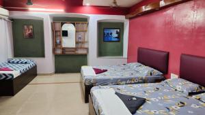 a room with three beds and a red wall at Southcanal Holidays in Alleppey