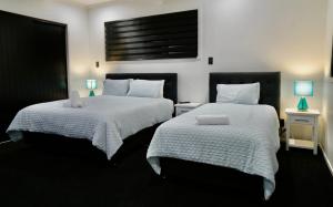 a bedroom with two beds with white sheets and blue lamps at A Dreamed Home Away From Home in Rotorua