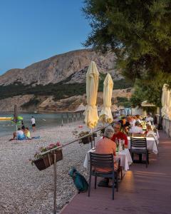 a group of people sitting at tables on a beach at Hotel Dobrovit in Baška