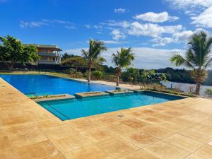a swimming pool with palm trees and a house at Cozy one bedroom apartment in a secure complex , PORT CHAMBLY Mauritius in Terre Rouge