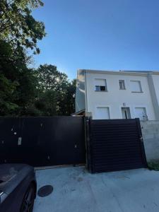 ein schwarzes Tor vor einem weißen Gebäude in der Unterkunft maison neuve au porte de paris in Bagneux