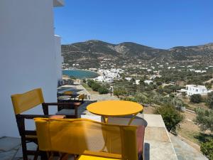 プラティスヤロス・シフノスにあるVenikouas Hotelの黄色のテーブルと椅子、景色を望むバルコニー